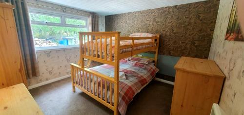 a small room with a bunk bed and a desk at Torcroft Lodges in Drumnadrochit