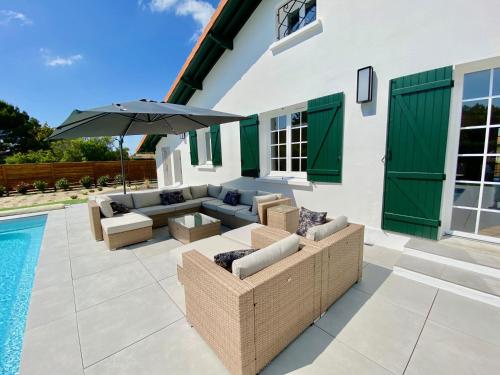 - une terrasse meublée avec un parasol à côté de la piscine dans l'établissement Villa familiale proche des plages avec piscine chauffée, à Mimizan