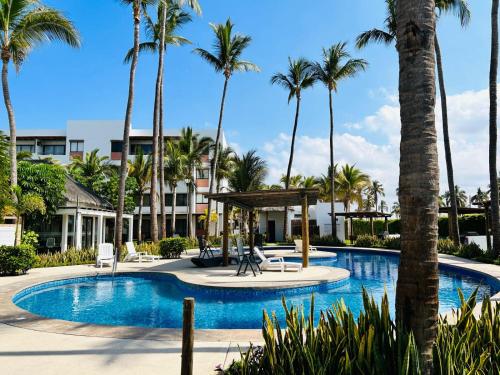 a pool at a resort with palm trees at Palmilla 301,depa 5 min de playa in Mazatlán