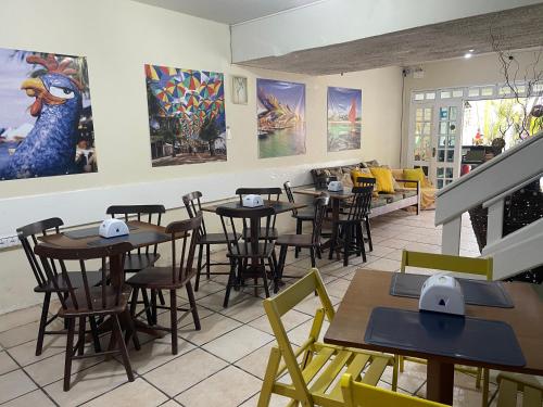 a restaurant with tables and chairs and paintings on the walls at Pousada Mananauê Beach in Porto De Galinhas