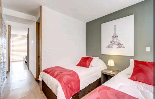 1 dormitorio con 2 camas con almohadas rojas y la torre Eiffel en Loft Contador, en Bogotá