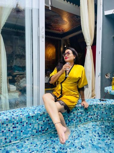 a woman sitting on top of a bed at Super luxury Gold Room with private pool at Homestay by the tea garden Dibrugarh in Dibrugarh