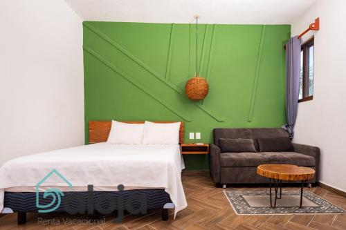 1 dormitorio con cama, sofá y pared verde en VIca Guest House con piscina en la entrada de la Zona Hotelera, en Cancún