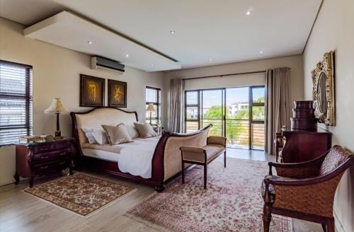 a bedroom with a bed and a chair and windows at Pearl House in Centurion