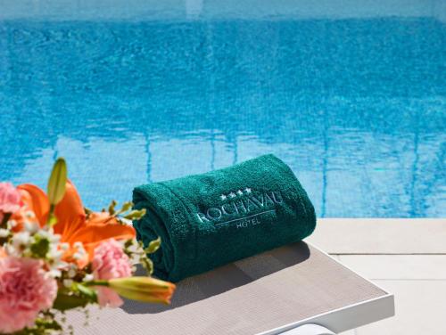 a green roll of towels next to a swimming pool at Rochavau Hotel in Portimão