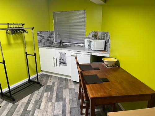 een keuken met een houten tafel en een magnetron bij Cozy room with full bathroom in Dagenham