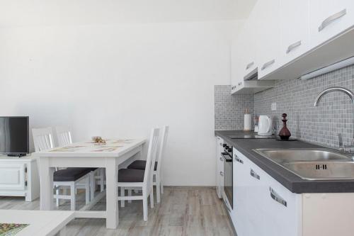 a white kitchen with a sink and a table at Put Marin in Zlarin