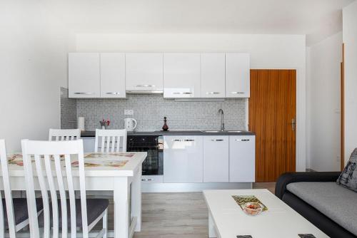a kitchen with white cabinets and a white table and chairs at Put Marin in Zlarin