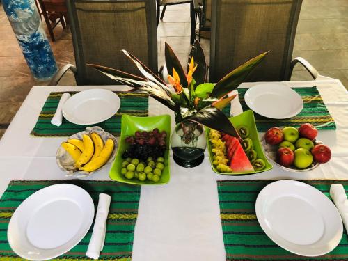 a table with white plates and fruit on it at Coral Cove Inn in Maya Beach
