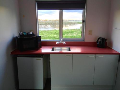 a kitchen counter with a sink and a window at North End Motel in Huntly