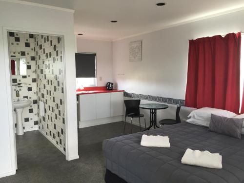 a bedroom with a bed and a table and a kitchen at North End Motel in Huntly