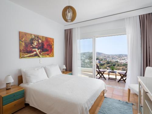 een slaapkamer met een wit bed en een groot raam bij Wild Pear Villa in Agia Pelagia