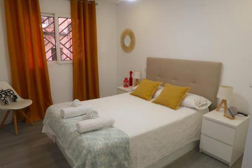 Un dormitorio con una cama blanca con almohadas amarillas y una ventana en Apartamento céntrico recién reformado en Murcia