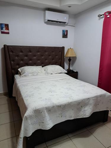 Un dormitorio con una cama grande con una manta. en Acogedora Casa, en Managua