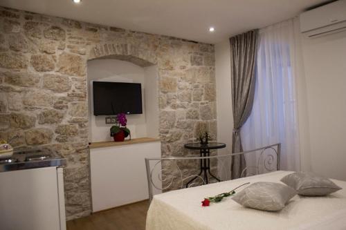una camera da letto con un muro in pietra, un letto e una TV di Sobe Jukić a Spalato (Split)