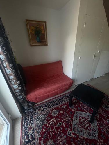 ein rotes Sofa im Wohnzimmer mit einem Teppich in der Unterkunft Duplex 4 personnes, ARMADA 2023 in Boos