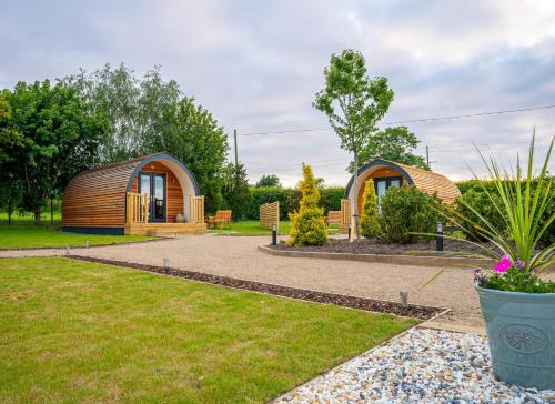 dois pequenos chalés de madeira num jardim em Willow Farm Glamping em Chester