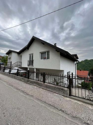 een wit huis met een hek aan de kant van de weg bij Apartman Royal sa GARAŽOM in Visoko