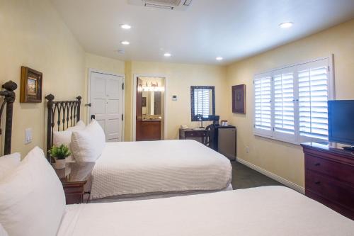 a bedroom with two beds and a window at Castillo Inn at the Beach in Santa Barbara