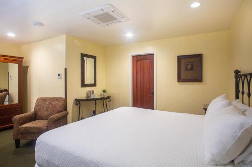 a bedroom with a large white bed and a chair at Castillo Inn at the Beach in Santa Barbara