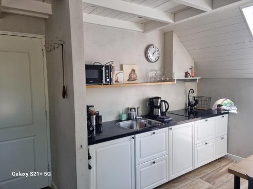 a kitchen with white cabinets and a sink and a clock at 't Achterhuis 