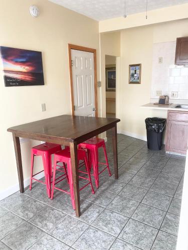 a kitchen with a wooden table and four pink stools at Abellona Inn & Suites in Old Orchard Beach