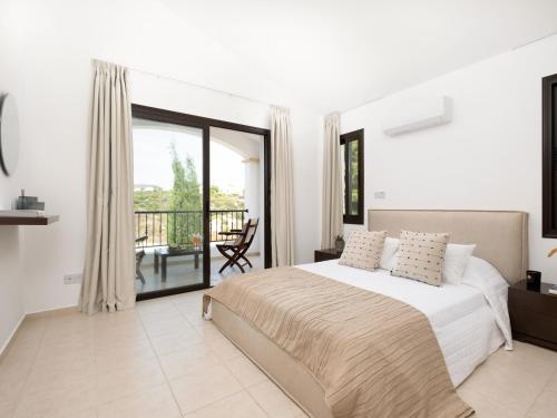 a white bedroom with a bed and a balcony at Sunny Paradise Luxury Villa With Pool & Hot Tub in Paphos City