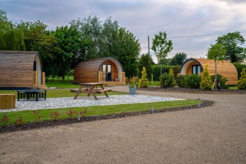 eine Gruppe von Lodges mit einer Bank und einem Picknicktisch in der Unterkunft Willow Farm Glamping in Chester