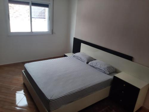 ein Schlafzimmer mit einem Bett mit gestreifter Bettwäsche und einem Fenster in der Unterkunft Apartment pour les familles avec 2 chambres in Al Hoceïma