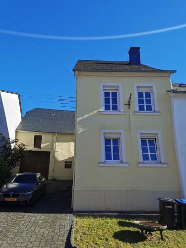 a white house with a car parked in front of it at Das Kirch24 - DAS Ferienhaus in Heidenburg in Heidenburg