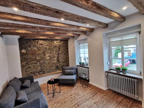 a living room with two couches and a stone wall at Das Kirch24 - DAS Ferienhaus in Heidenburg in Heidenburg
