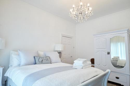 a white bedroom with a white bed and a chandelier at Super Stylish Flat Very Close to Freeman Hospital! in High Heaton