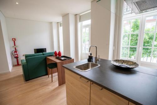 uma cozinha com um lavatório e uma sala de estar em HAGAH Alojamentos em Guimarães