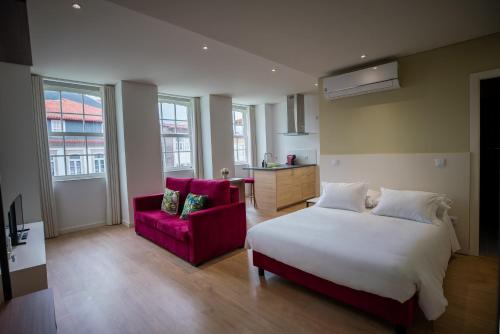 een slaapkamer met een wit bed en een rode bank bij HAGAH Alojamentos in Guimarães