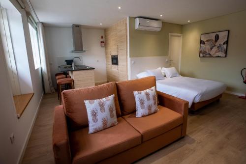 a hotel room with a bed and a couch and a kitchen at HAGAH Alojamentos in Guimarães
