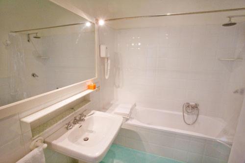 een badkamer met een wastafel, een bad, een witte wastafel en een toilet bij Malìa bed and breakfast in Lecce