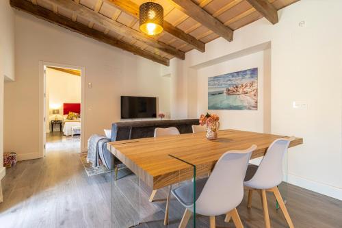 a dining room with a wooden table and white chairs at Casa Palacio Rufina & Jardines in Jerez de la Frontera