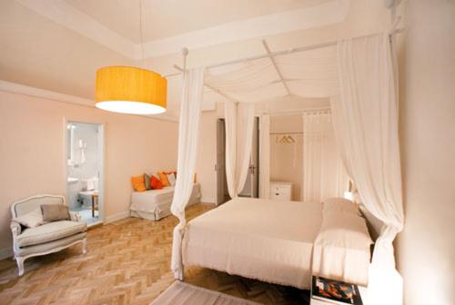 een slaapkamer met een wit hemelbed en een stoel bij Malìa bed and breakfast in Lecce