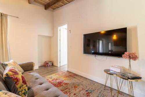 a living room with a couch and a tv on the wall at Casa Palacio Rufina & Jardines in Jerez de la Frontera