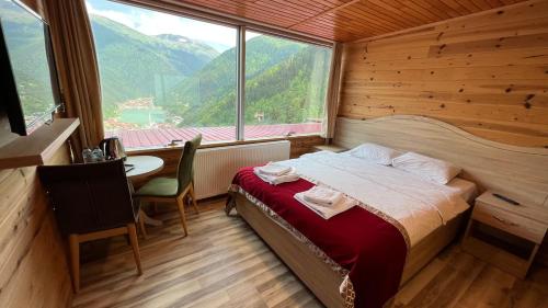 a bedroom with a bed and a table and a window at Kar Hotel Uzungöl in Uzungol