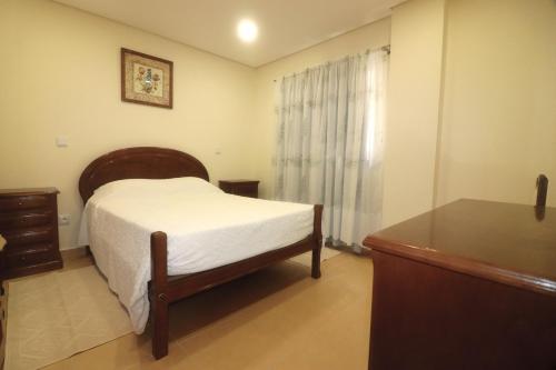 ein Schlafzimmer mit einem Bett, einer Kommode und einem Fenster in der Unterkunft Casa dos Meoes in Geres