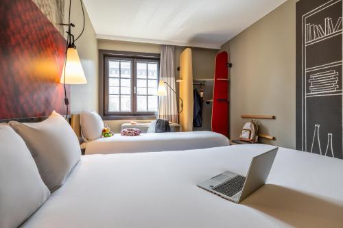 a hotel room with two beds and a laptop on a desk at ibis Hotel Brussels off Grand'Place in Brussels