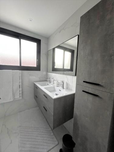 une salle de bain blanche avec un lavabo et un miroir dans l'établissement LA MAISON DE MARIE A 8 mn des plages, à Perpignan