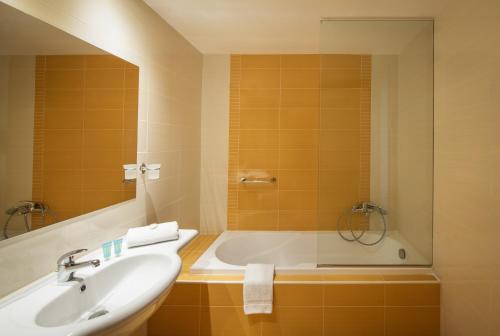 a bathroom with a sink and a bath tub at Mitsis Bali Paradise Hotel in Balíon