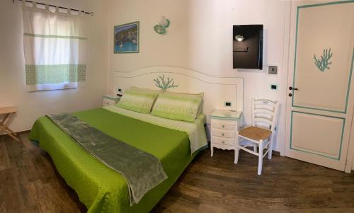 1 dormitorio con cama verde, mesa y silla en B&B da Miranna, en Dorgali
