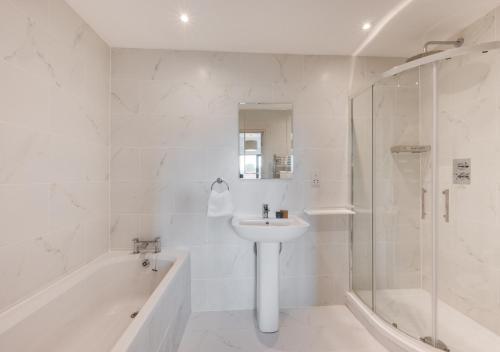 a white bathroom with a sink and a shower at The Grainstore in Briston