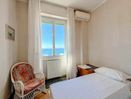 1 dormitorio con 1 cama, 1 silla y 1 ventana en Grande Appartamento Vista Mare, en Varazze