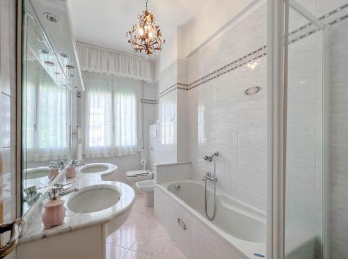 uma casa de banho branca com uma banheira, um lavatório e um chuveiro em Grande Appartamento Vista Mare em Varazze