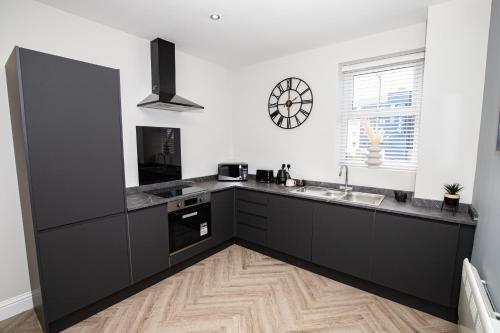 cocina con armarios negros y suelo de madera en Church Street Apartments en Hartlepool