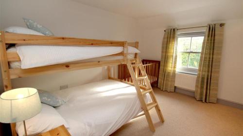1 Schlafzimmer mit 2 Etagenbetten und einer Lampe in der Unterkunft Orchard Cottage, Landimore in Cheriton